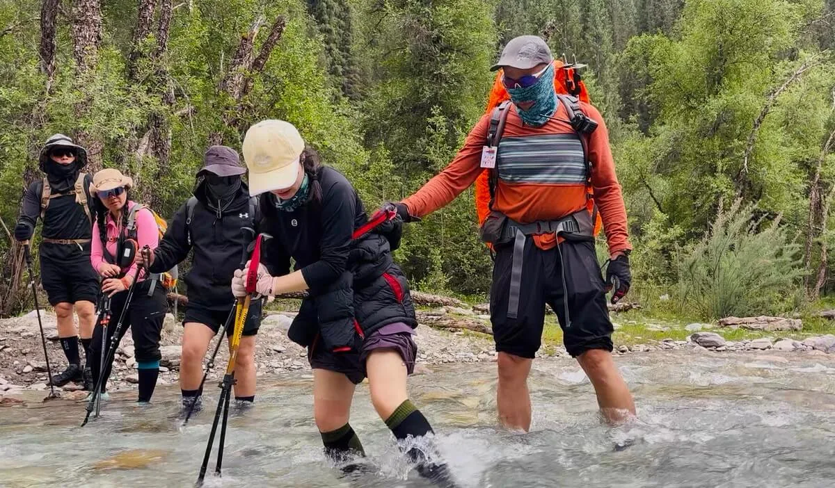 Group hiking through water wearing waterproof socks