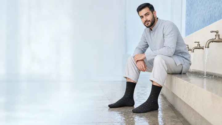 Middle Eastern Muslim model wearing black Wudu or Wudhu waterproof socks on a clean wet floor